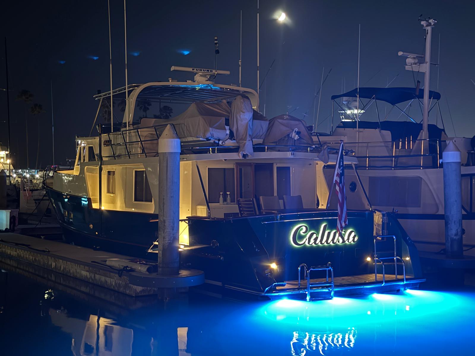 Halo-lit Calusa script lettering on the transom of a yacht docked at night