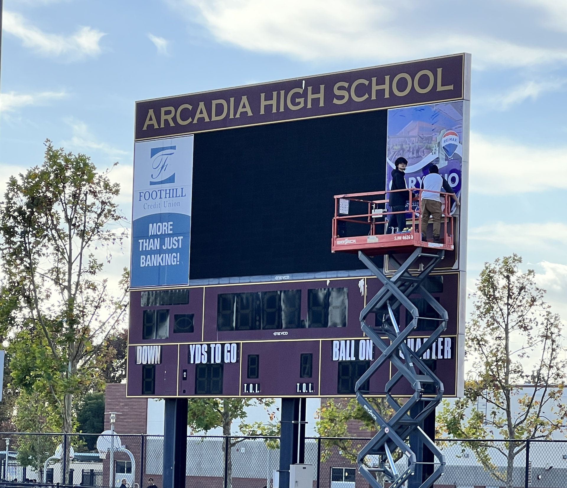 Arcadia High School stadium scoreboard in maroon and gold with video display and sponsor panels during installation