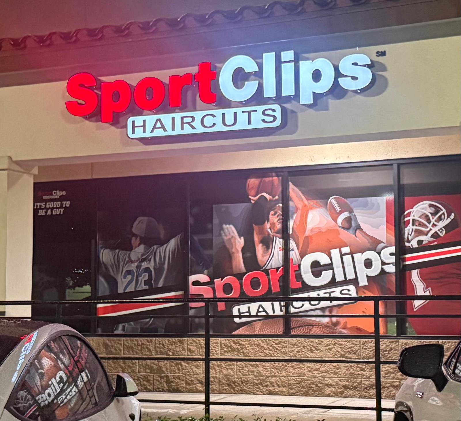Illuminated red and white Sport Clips Haircuts channel letters above a storefront